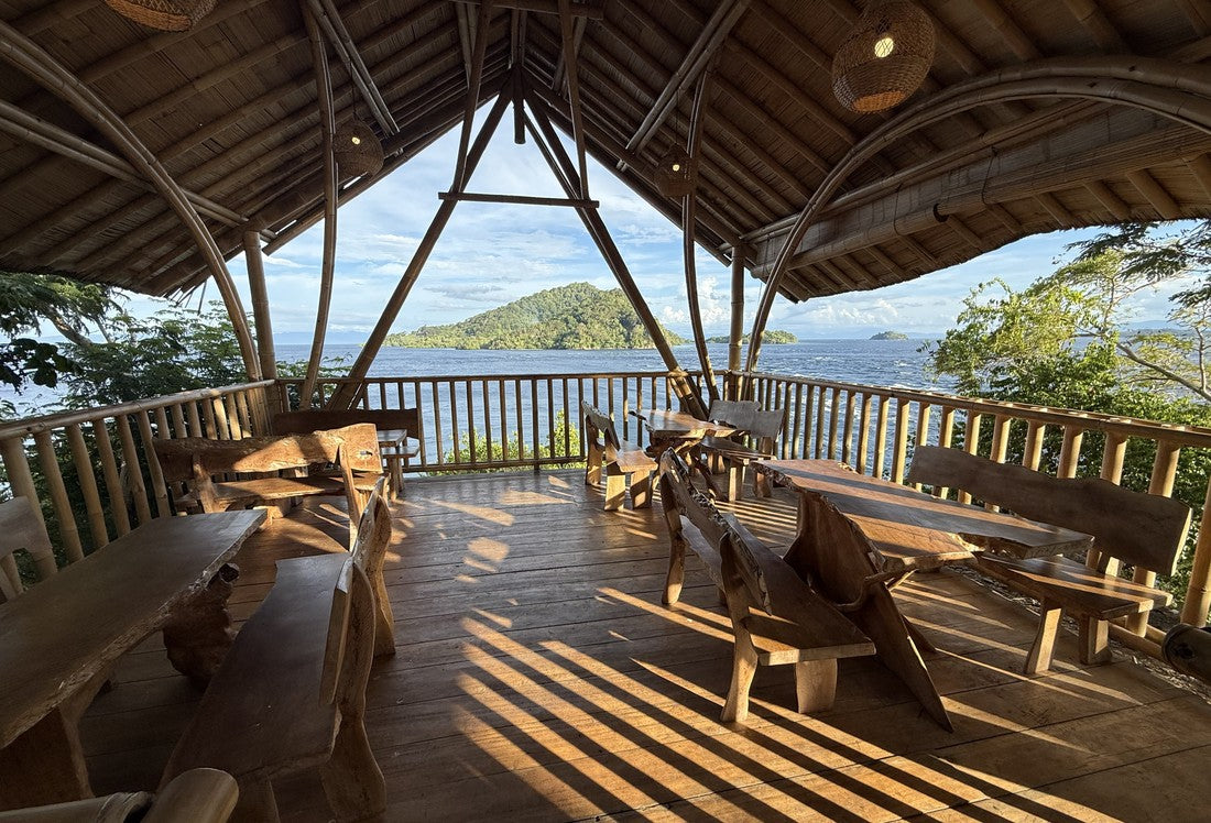 An open-air bamboo resort pavilion overlooking the ocean at a dive trip destination