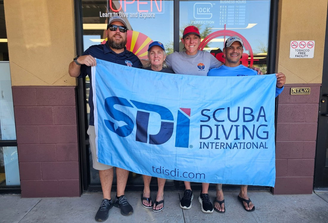 Dive Arizona staff holding an SDI Scuba Diving International flag outside the shop